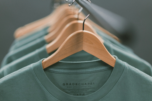 Green eco friendly t-shirts on wooden hangers